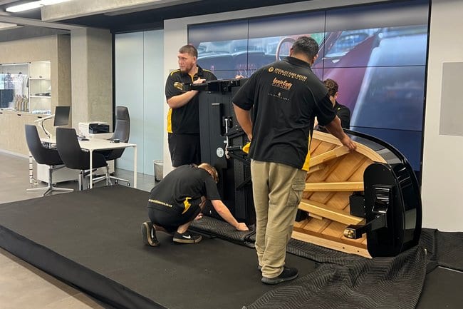 Specialist Piano Movers crew handling a grand piano in a Lewis Eady showroom
