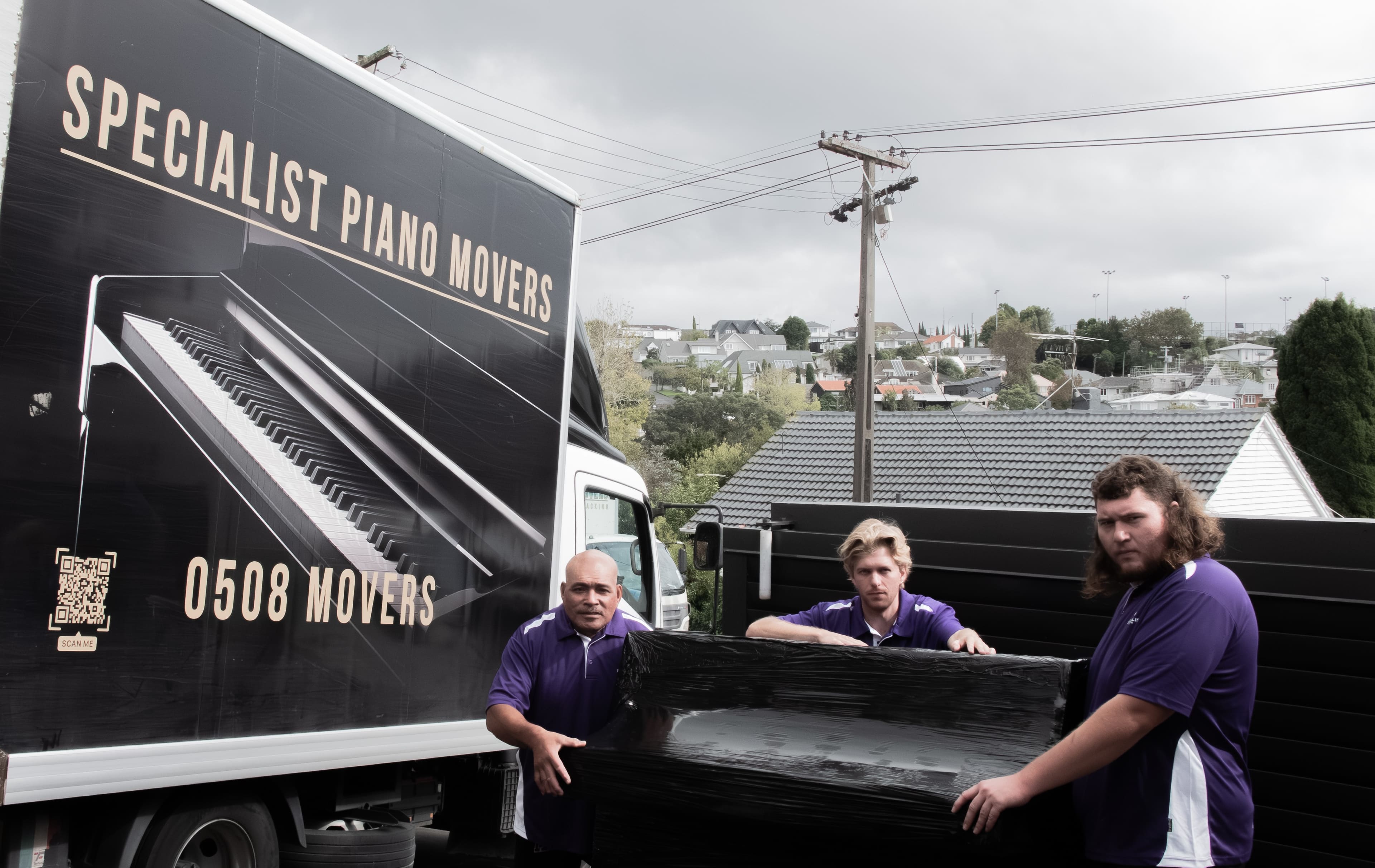 Specialist Piano Movers team with a wrapped piano beside the company truck