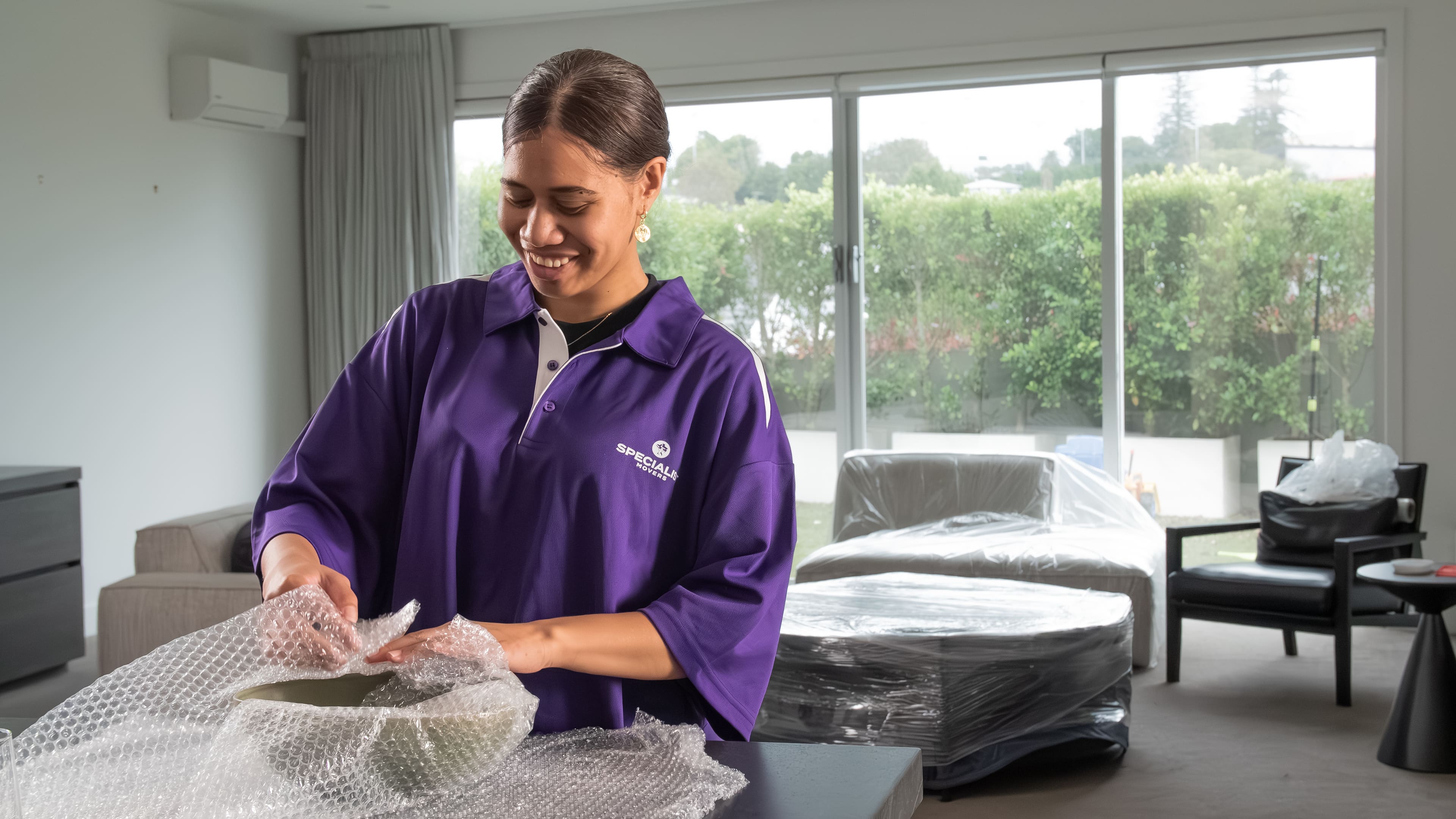 Crew moving wrapped furniture into a home